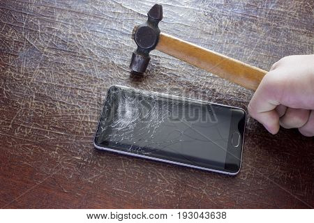 Hammer in hand next to the phone with a broken screen