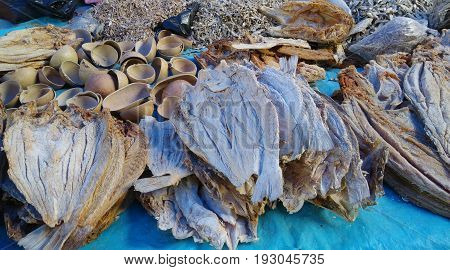 Stacks of dried fish filets and squash bowls on blue background on market day, Oaxaca, Mexico.
