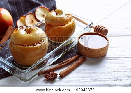 Composition with tasty baked apples and cinnamon on light wooden table, closeup