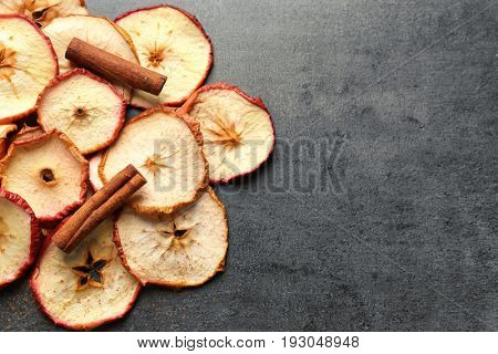 Composition with apple chips and cinnamon on dark table