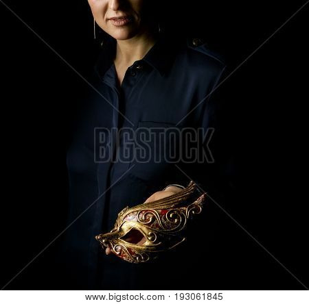 Coming out into the light. woman in the dark dress isolated on black showing Venetian mask