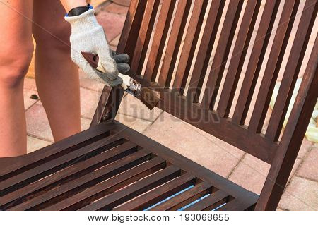 Painting and applying protective varnish on a wooden garden chair