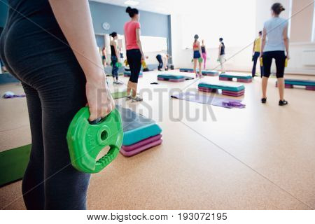 Girl athlete keeps the disc from the bar weighting agent for doing crossfit and fitness. Concept of sports equipment and weight loss.