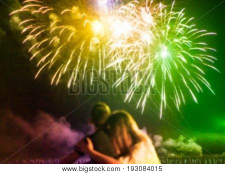 Blurred couple watching firework on top of the roof outdoor - Young lovers having romantic tender moments on the beach at festival summer event - Love and romance concept - Defocused image