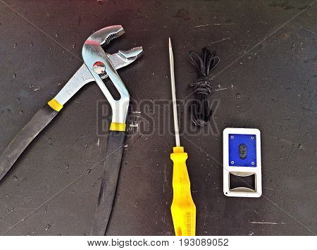 Tools, screwdriver pliers, lantern and black rope on steel floor