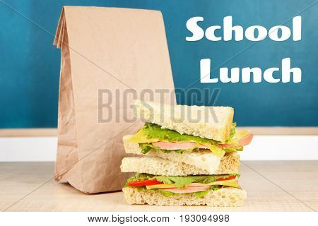 School lunch concept. Tasty sandwiches with paper bag on wooden table at classroom
