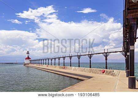 An elevated metal catwalk leads to the East Pierhead Lighthouse at Michigan City Indiana on a partly cloudy summer afternoon.