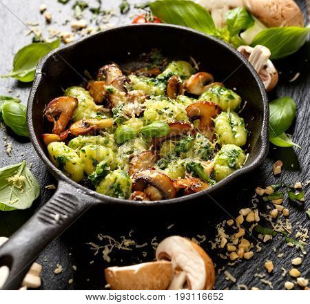 Potato gnocch with addition of herb pesto, cheese and mushrooms on cast iron frying pani, delicious vegetarian dish