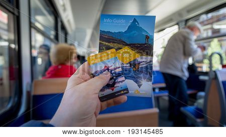 ZERMATT, SWITZERLAND - May 16. 2017: Gornergrat booklet and ticket in hand in the Red train climbing up to Gornergrat station on Zermatt, Switzerland.