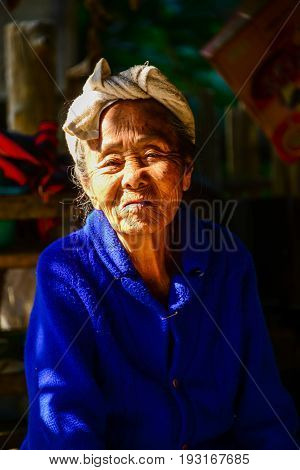 CHIANGMAI THAILAND - JANUARY 24 2015: Indigenous senior woman in light and shadow looking to visitors in Mae Chaem of Chiangmai Thailand