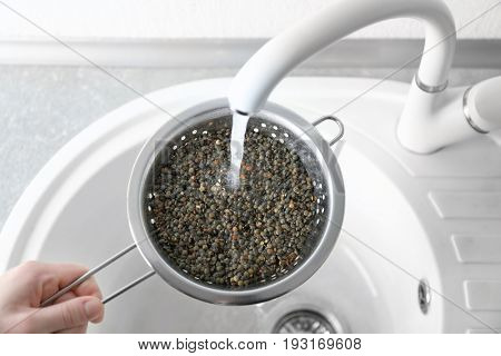 Washing raw lentils with tap water before cooking in kitchen