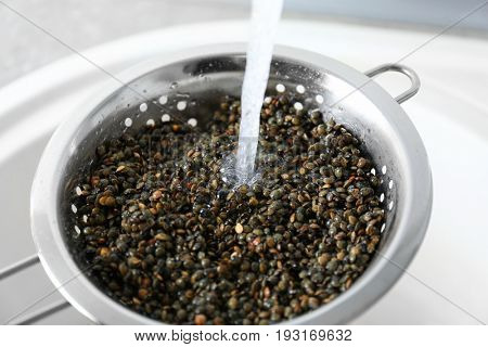 Washing raw lentils with tap water before cooking, closeup