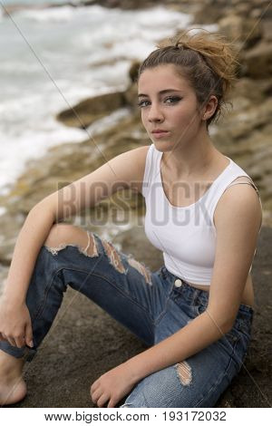 Teenage Girl Sitting On The Rocks.
