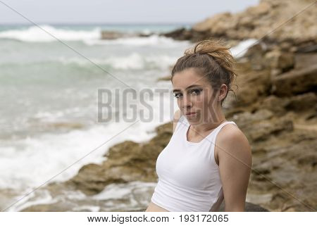 Teenage Girl Sitting On The Rocks.
