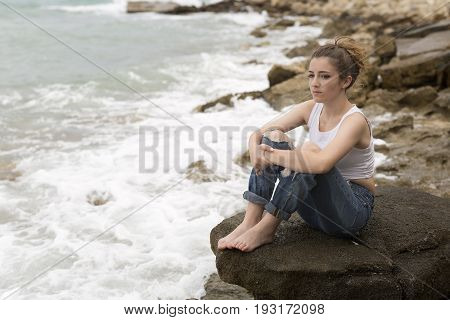 Teenage Girl Sitting On The Rocks.