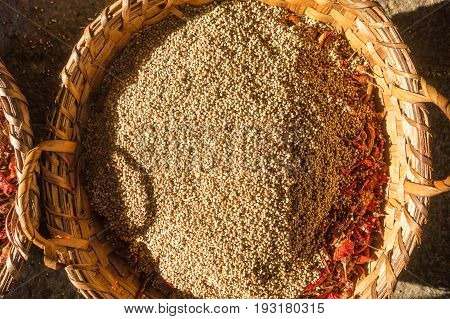 A wicker basket with many fried whole coriander seeds and chili peppers. Preparation for the feast in a Hindu temple