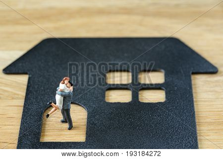 Miniature happy couple family figure standing on paper house with calculater as property or financial mortgage plan concept.