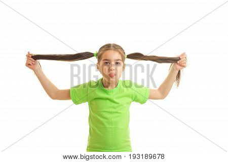 funny little girl in green shirt holdin her tails in hands and showing tonque