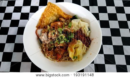Spicy curry instant noodles soup with fork on wooden dining table