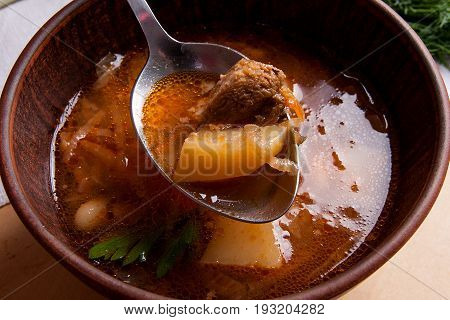 Close Up View Of Clay Plate And Spoon With Red Beetroot Soup Or Borsch On Wooden Background..
