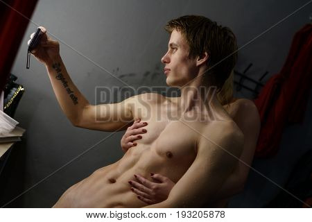 Athletic handsome man with naked torso making selfie in studio