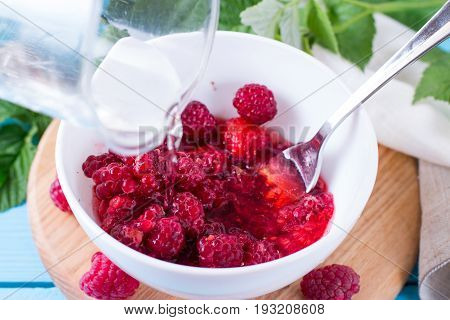 Preparation of raspberry jam on a wooden background