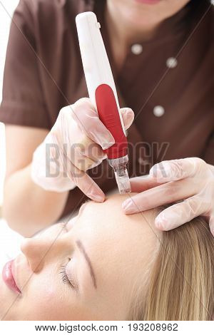 Needle mesotherapy treatment aesthetic execution in the beauty salon
Beautician performs a needle mesotherapy treatment on a woman's face