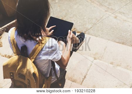 Hipster young girl with bright backpack and vintage camera using tablet or holding gadget planning travel plan. View tourist traveler on background Parc Laberint Barcelona. Mock up for text message