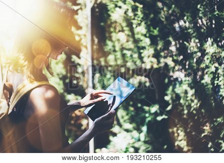 Hipster young girl with bright backpack and vintage camera using tablet or holding gadget planning travel plan. View tourist traveler on background Parc Laberint Barcelona. Mock up for text message
