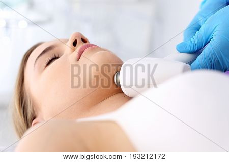 Firming the skin of the neck. The vacuum neck massage using a special head. Woman in the clinic of aesthetic medicine.