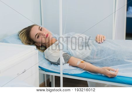 Pensive woman transfused lying in hospital ward.