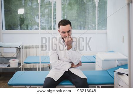 Thoughtful doctor sitting in a operating room with his hand on head.