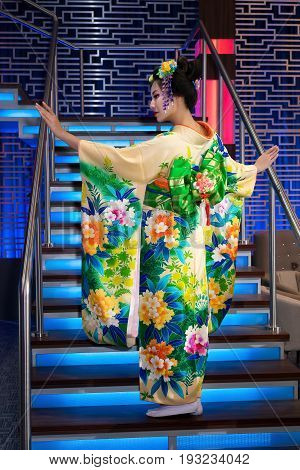Geisha in traditional chinese floral kimono with bow, standing on a staircase