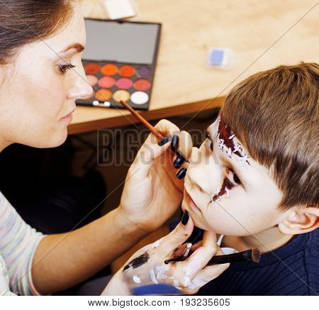 little cute child making facepaint on birthday party, zombie Apocalypse facepainting, halloween preparing concept, lifestyle people close up