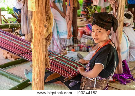 CHIANGMAI THAILAND - JANUARY 24 2015: Hill tribe girl demonstrating weaving fabric in 22nd Traditional Skirt Fabric and The Indigenous Product and Culture Festival in Mae Chaem of Chiangmai Thailand