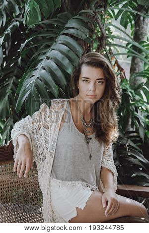 Portrait of a beautiful girl in the leaves of a palm tree in an Asian countryside