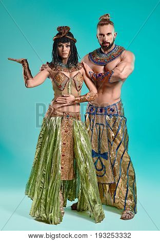 The man and woman in the images of Egyptian Pharaoh and Cleopatra on blue studio background