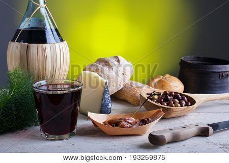 Italian slow food on the white table. Olives cheese bread anchovies and red wine