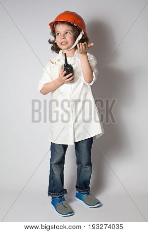 Young curly superintendent said on the radio looking up. Gray background.