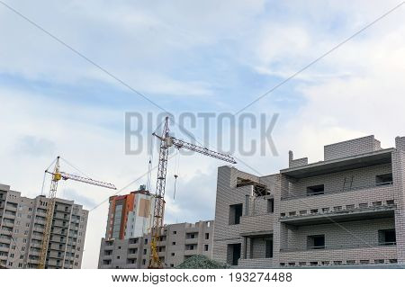 High yellow crane building a house in the blue sky with clouds.