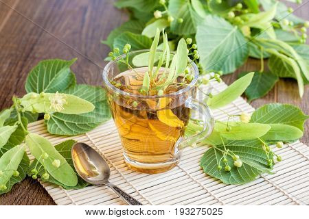 Lime flower tea in glass cup with linden flowers. midicinal remedy.
