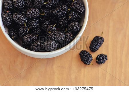Summer berries in a pialat on wooden background close-up