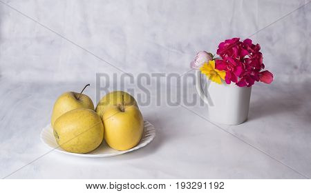 Apples and flowers in coffee cup on the table