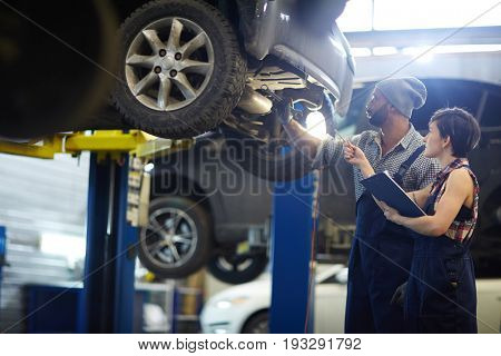 Master of car service consulting his trainee in workshop