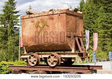 Bad Gastein Austria - JUNE 08 2017: Old mining truck in front of the Health resort Heilstollen a former mining tunnel. Near Bad Gastein Austria Europe. Hammer and pick as symbols of mining.