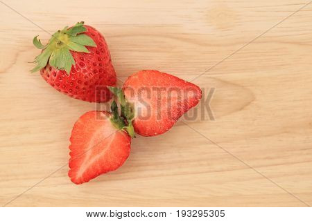 Fresh strawberries full body and halves on wooden background.