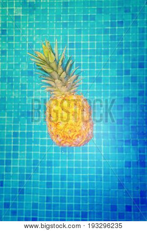 Whole yellow pinapple in pool blue cool water, retro toned