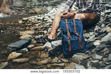 Unrecognizable Male Hiker Sits On River And Enjoys Surrounding View Exporing Adventure Hiking Concept