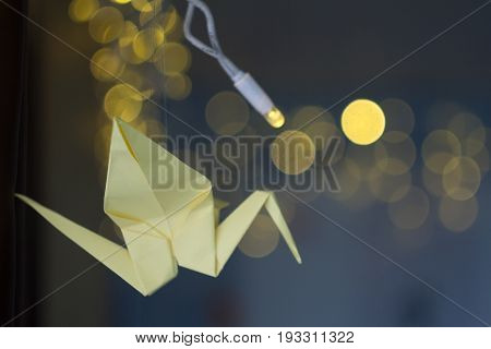 Paper yellow crane origami on a dark Christmas background garland.