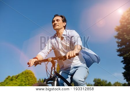 Freedom of speed. Inspired enthusiastic active man keeping up the speed while riding a bicycle and enjoying the warmth of the day outdoors